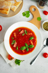 Plate with delicious tomato soup on light background