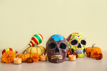 Painted human skulls with flowers, candles and pumpkins on beige background. El Dia de Muertos