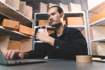 man watching and checking the online order for shipping the parcel to customer drinking a coffee. man working with new business about online shopping in home office and small store.