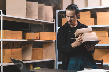 working man checking the online order on his laptop and take a note. man working with new business about online shopping in home office and small store.