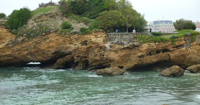 Traveling shot of the seaside resort of Biarritz with a boat passing between the rocks