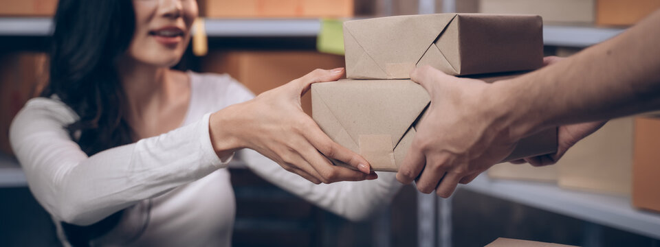 banner background of businesswoman receiving parcels from delivery man with happiness from shipping company. Young women with new business about online shopping in home office and small store.