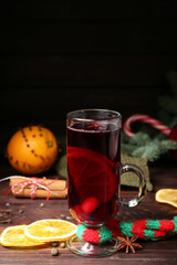 Glass cup of aromatic mulled wine on dark wooden background