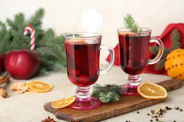 Wooden board with glasses of tasty mulled wine on light background