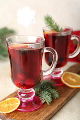 Wooden board with glasses of tasty mulled wine on light background, closeup