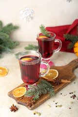 Wooden board with glasses of tasty mulled wine on table