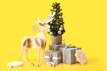 Wooden reindeer with Christmas tree and presents on yellow background