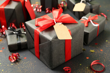 Gift box with price tag on dark background, closeup. Black Friday sale