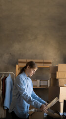 Online store selling clothes on website. ecommerce business from home. Woman packing new clothing...