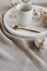 Obraz na płótnie Canvas Beige knitting blanket, Christmas tree decorations and cup coffee on marble tray .Xmas scene stationery still life neutral colors.Copy space