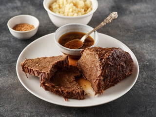 Roast beef, beef stew, sliced fried piece of beef with sauce on a plate.