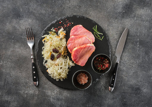 Backed Kasseler pork steak with sauerkraut. Smoked pork lion. Sliced smoked pork chop on wooden board