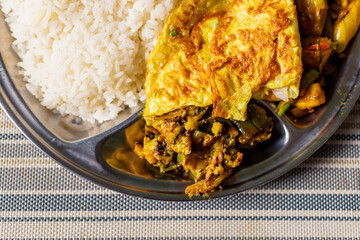 Steamed rice lentil dal mix vegetables Indian curry and an omelet on a lunch plate Bengali lunch...