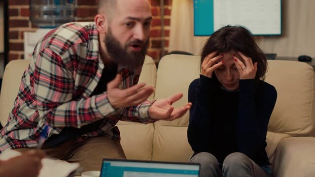 Unhappy woman attending couple therapy session with husband, fighting over relationship problems. Having argument at counseling appointment with psychoanalysis consultant at psychotherapy.