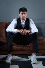 Portrait of a good looking Asian man sitting on the sofa