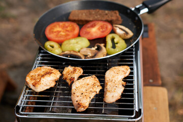 Cooking meat and vegetables on a portable grill. Picnic outdoors. 