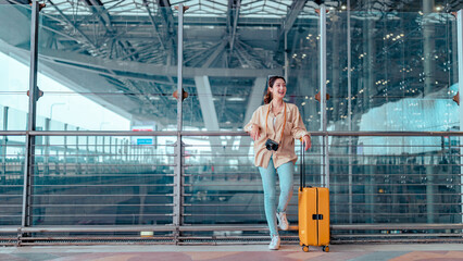 Happy attractive asian woman passenger traveler with a yellow suitcase at the modern airport terminal, copy space, Tourist journey trip concept