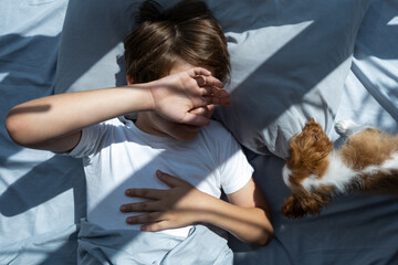 boy with a dog in an embrace lies in bed in morning. Sleep with pets. cute puppy cavalier king...