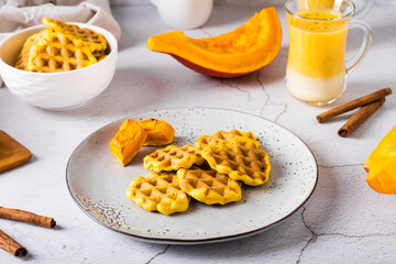 Belgian homemade pumpkin waffles on a plate on the table. Autumn baking.