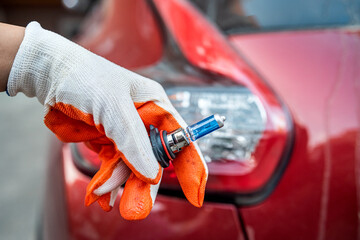 car lamp in a hand on the background of a car headlight.