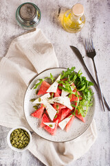 Homemade salad of feta cheese, watermelon and arugula on a plate. Organic diet. Top and vertical