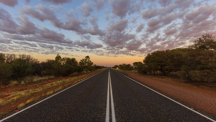 Straight line on an Australian highway through the outback at dusk
