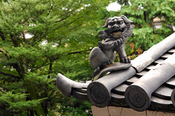 獅子の瓦がユニークな日本の緑と瓦屋根のある景色。