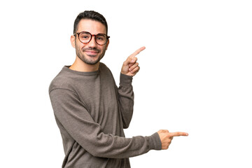 Young handsome caucasian man over isolated background pointing finger to the side and presenting a...