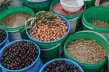 a lot of olives on the market in barrels background