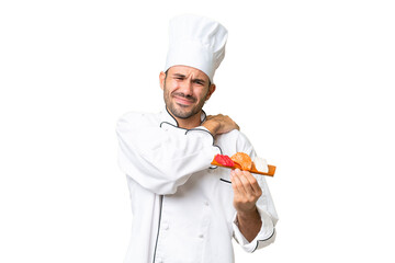 Young caucasian chef holding a sushi over isolated background suffering from pain in shoulder for having made an effort