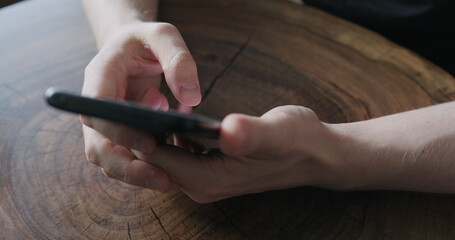 Closeup young man use smartphone while sitting at the table