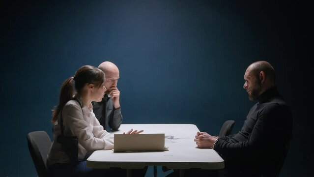 Police detective abruptly stands up, slams fist on table and shouts at suspected man in handcuffs. Interrogation of criminal. Murderer is afraid of FBI agent's threats and is ready to tell everything