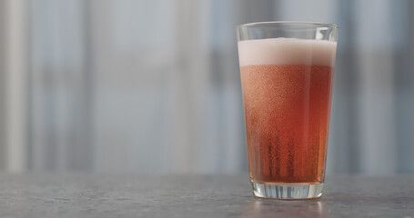 pour orange fizzy drink into pint glass on concrete countertop with copy space