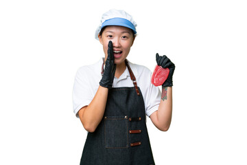 Young caucasian woman wearing an apron and serving fresh cut meat over isolated background shouting with mouth wide open