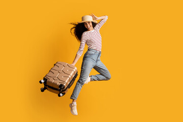 Time To Travel. Cheerful Young Woman Wearing Wicker Hat Jumping With Suitcase