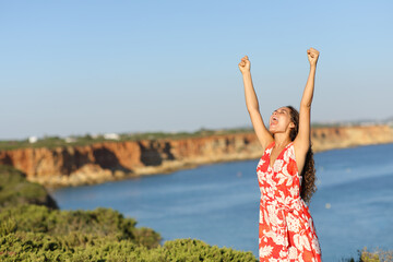 Excited tourist on the beach raising arms celebrating vacation