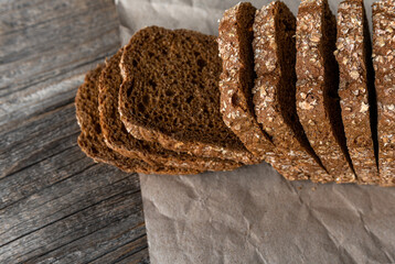 Fototapeta na wymiar Rye bread with bran on paper and wooden background.