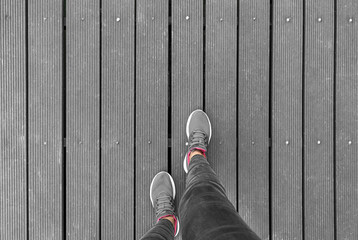 Legs in sneakers on a wooden platform. There is space for text.