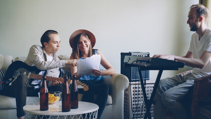 Attractive female vocalist and cheerful male guitarist are reading song lyrics and laughing while...