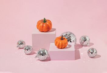 Autumn halloween creative layout made with pumpkins and disco ball decoration on cubes on pastel...