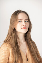 Fototapeta premium Fashion, beauty and make-up concept. Beautiful long hair brunette woman looking to camera with smile. Studio close-up portrait. Model wearing beige soft sweater