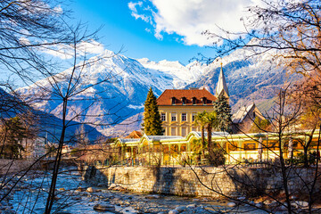 MERANO,ITALY - January 6, 2022. Merano o Meran is a city and comune in South Tyrol, northern Italy. Generally best known for its spa resorts. Passer River, Alps mountains in winter time. - obrazy, fototapety, plakaty