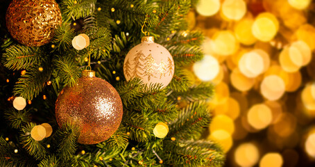 Obraz na płótnie Canvas Decorated Christmas tree with sparkling balls on blurred golden background with bokeh.