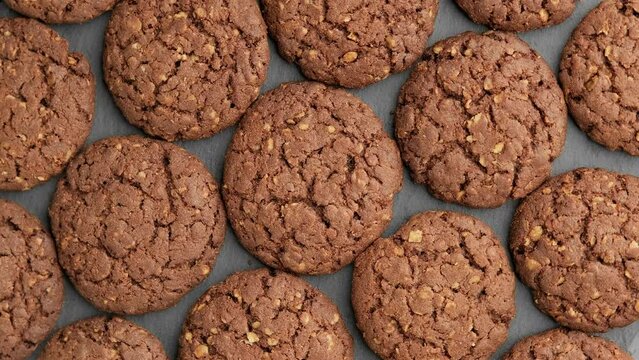 Brown cookies on dark background. Top view of rotating fresh homemade cookies. Group of oatmeal cookies. Food concept. 4K, UHD