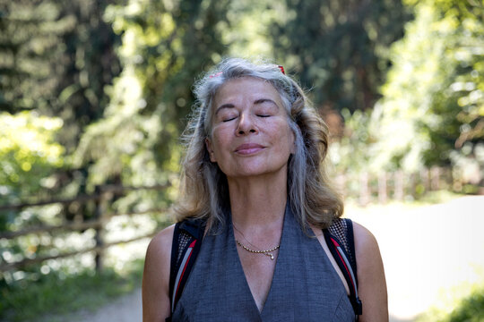 Senior Woman With Eyes Closed Inhaling Fresh Air In Forest