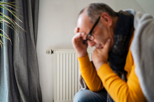 Depressed man with radiator in background at home
