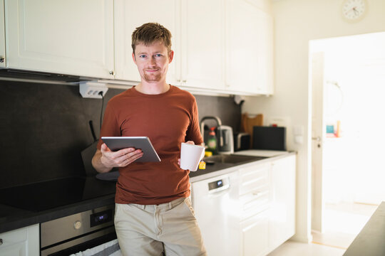 Man with table PC and coffee cup in kitchen at home