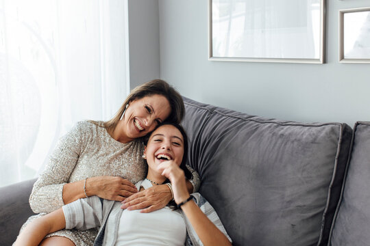 Mother and daughter laughing on sofa in living room at home