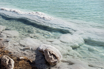 mineral salts chrystallizing around boulders in the industrial evaporation pond area of the Dead...