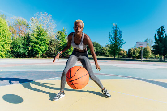 Young sportswoman dribbling basketball in sports court